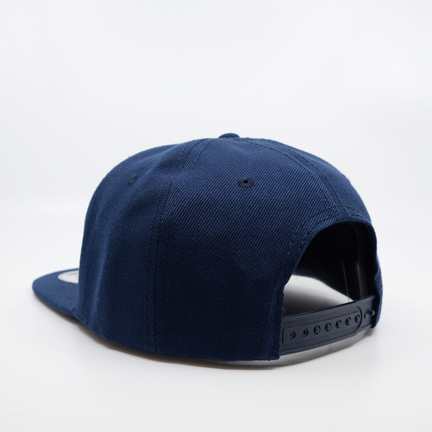 A navy blue snapback cap featuring a curved brim and an adjustable strap at the back. Logo visible on the side.