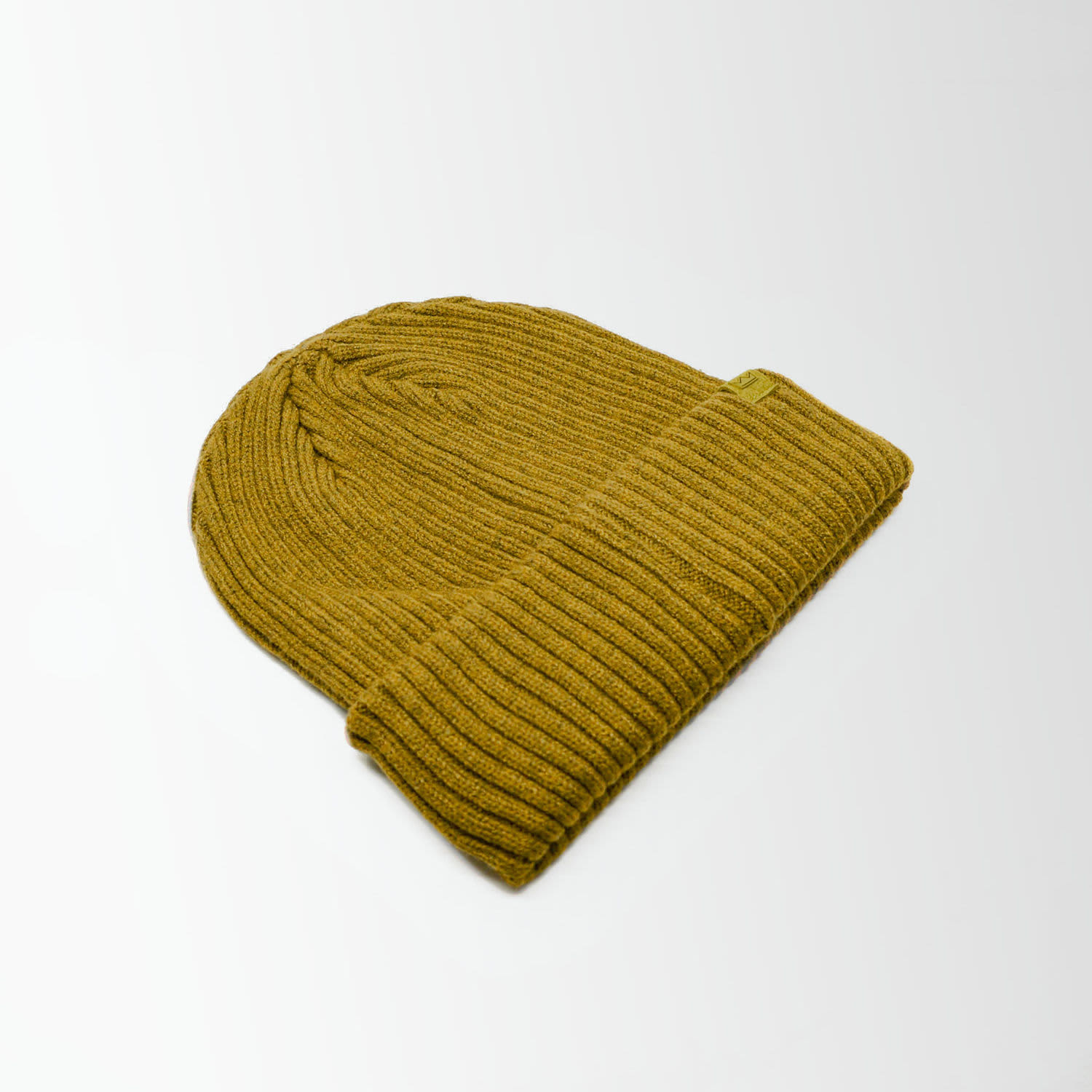 A green ribbed beanie, folded at the cuff, showcasing a simple design and texture.