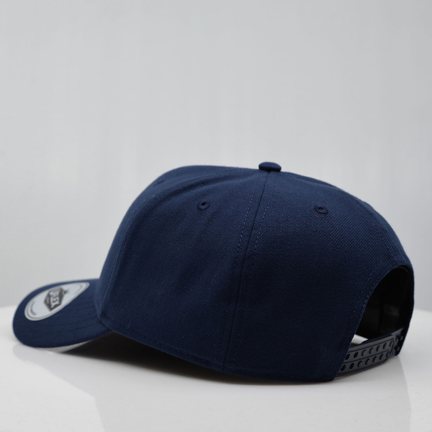 A navy blue six-panel snapback cap with a branded logo, featuring a flat brim and adjustable strap at the back.