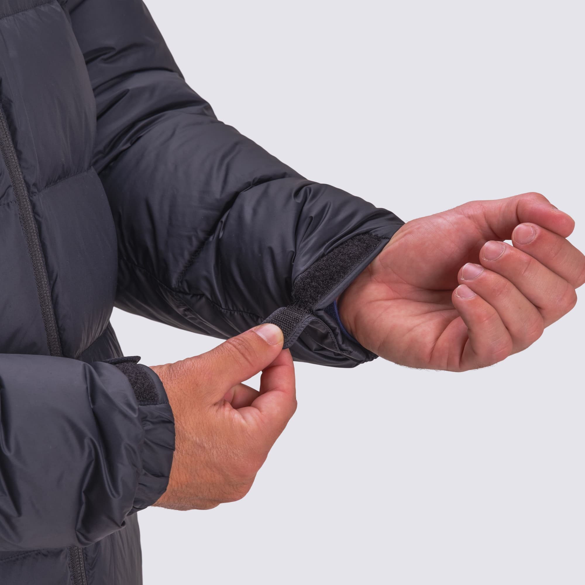 A close-up of a black puffer jacket's sleeve with adjustable Velcro cuff being fastened.