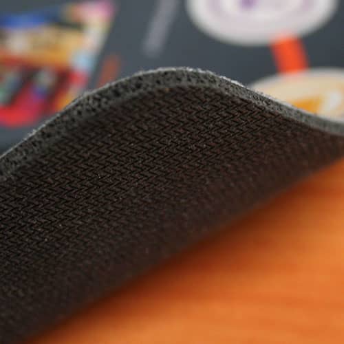 A textured black mouse mat with a fabric top, showcasing a slight curve at the edge.