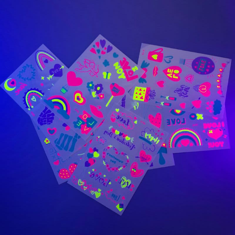 A collection of glow-in-the-dark temporary tattoos, featuring vibrant designs in pink, green, and blue on a dark background.