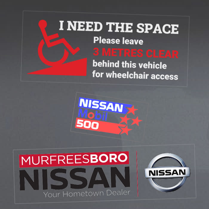 Assorted vinyl stickers featuring a wheelchair access symbol, a racing logo, and a car dealership logo with silver details.