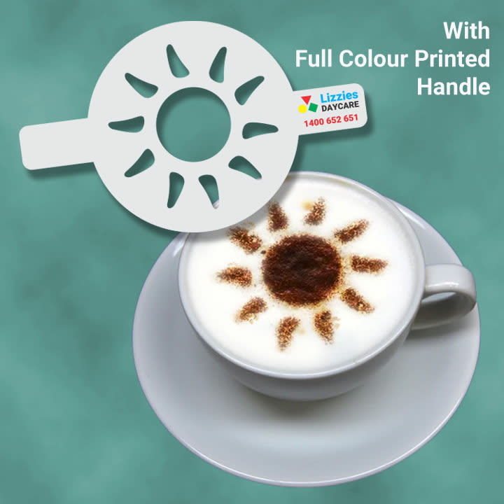 A coffee stencil in white placed over a frothy coffee with a sun pattern. The stencil features a full-colour printed handle.