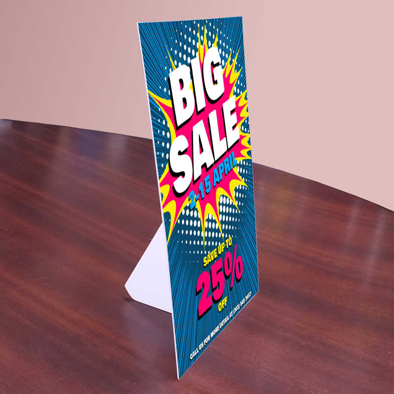 A promotional counter card featuring bright colours with a bold design, displaying a sale announcement.