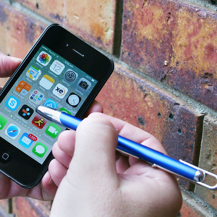 A blue stylus pen is being used on a smartphone screen, set against a textured brick wall.