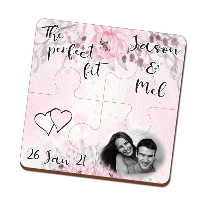 A pink four-piece MDF coaster puzzle featuring floral designs, two names, and a heart graphic. Includes a logo.