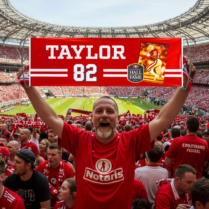 A fan holds a red banner in a stadium, surrounded by cheering supporters, showcasing a player and the Hall of Fame emblem.