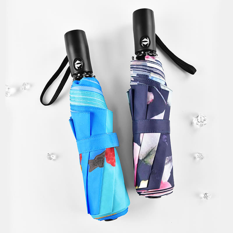Two compact umbrellas, one in blue with a colourful design and the other in navy with a floral pattern, both with handles and branding.