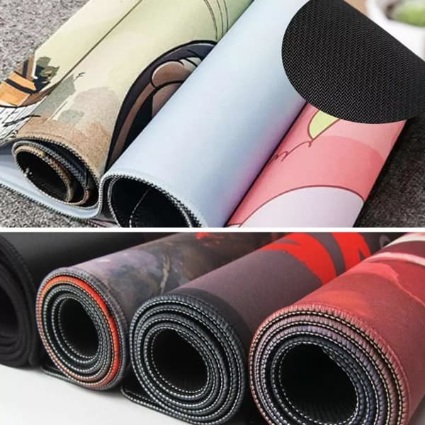 Rolled gaming mats in various colours, featuring textured surfaces and a smooth underside, alongside others with a black finish.