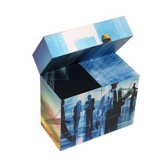 A promotional cube in blue and gradient hues with an open top, featuring images of people and buildings.