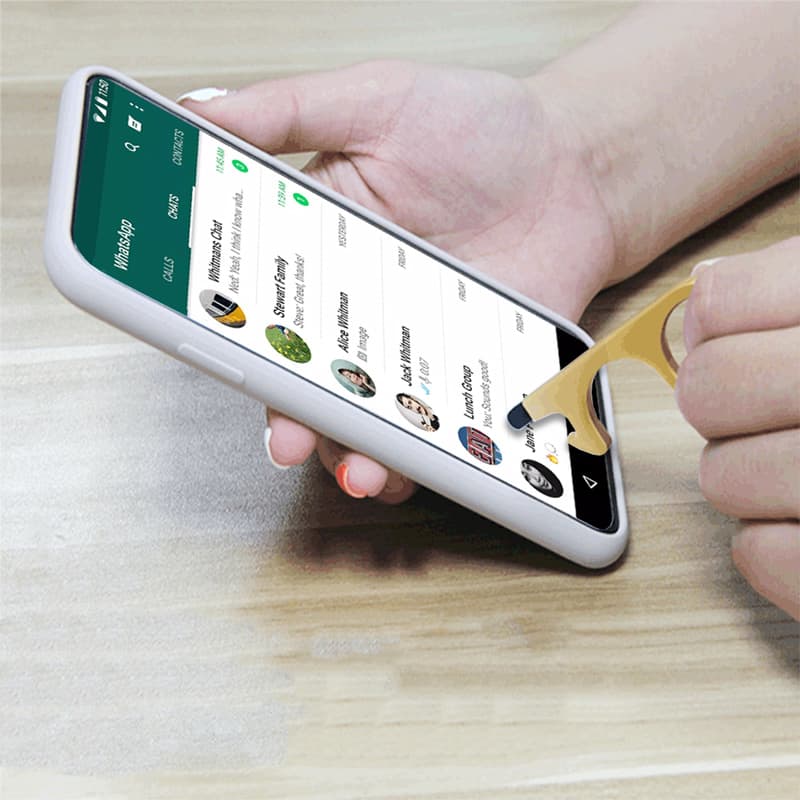 A gold stylus door opener in use on a smartphone, featuring a classic design against a wooden surface.