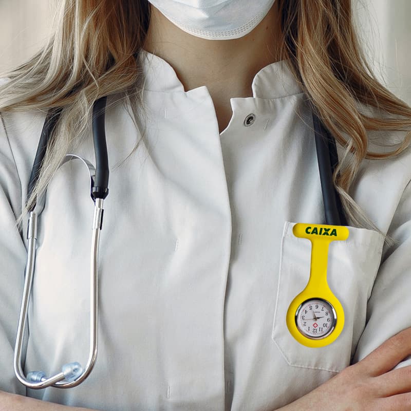 A silicone nurse watch in bright yellow is displayed on a white lab coat, alongside a stethoscope.