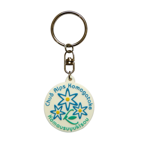 A round, soft PVC keyring featuring blue and green flowers, attached to a silver metal keychain with branding.