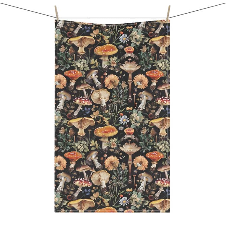 A tea towel featuring a vibrant mushroom and floral pattern with a dark background and natural colours.