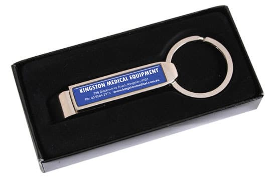 A drink bottle opener in silver sits within a black gift box, featuring a branding logo on its side.