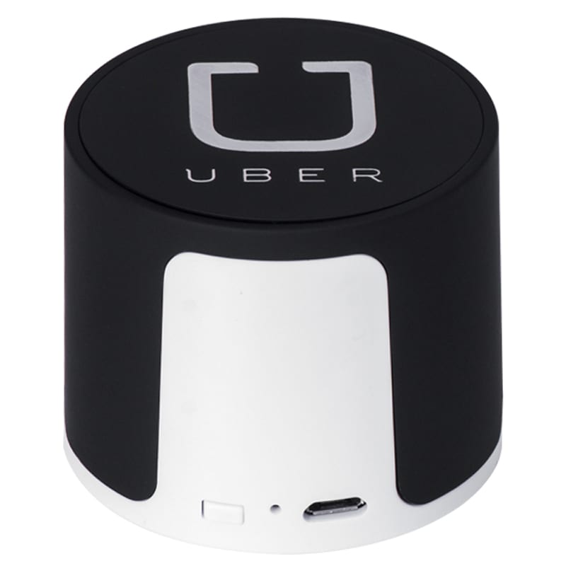 A wireless speaker in black and silver, featuring a logo. Compact design with a USB port.