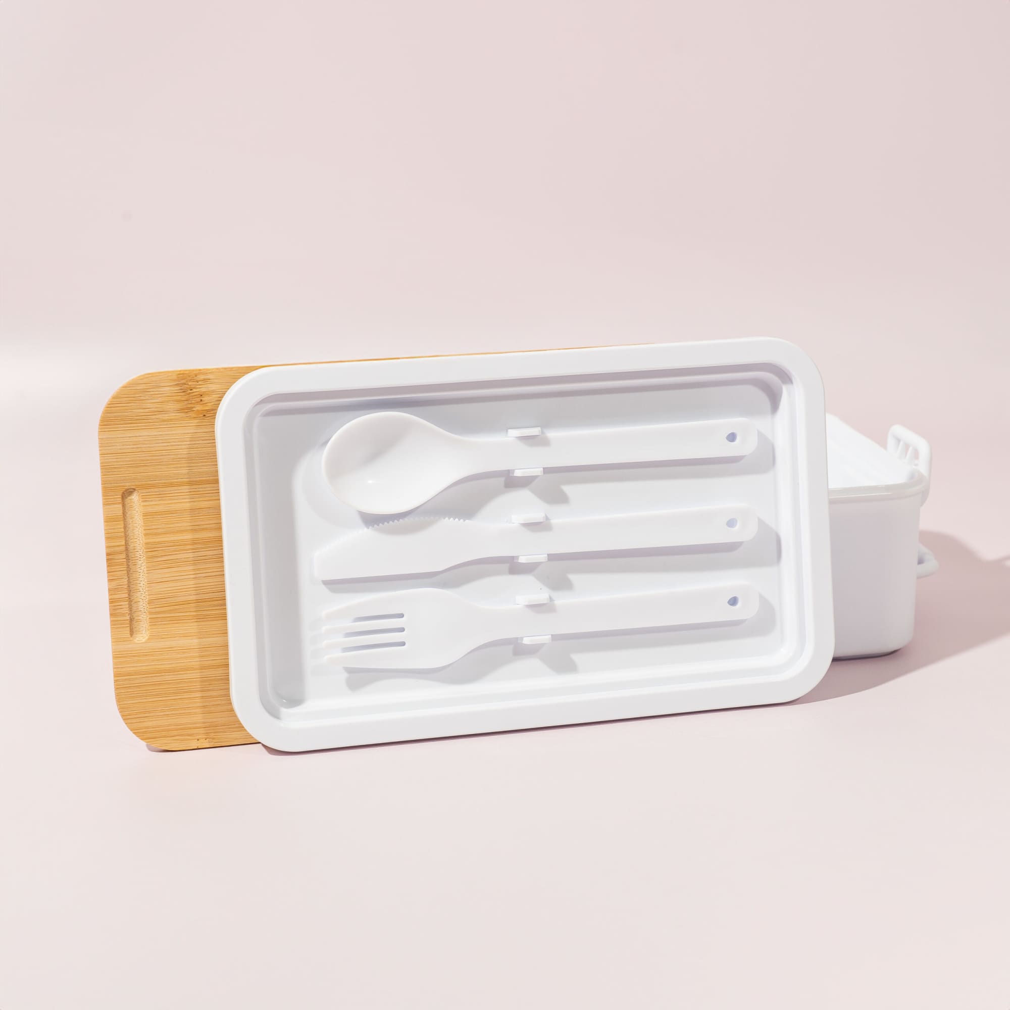 A double stack lunch box in white with a bamboo lid, featuring a spoon, fork, and knife included.