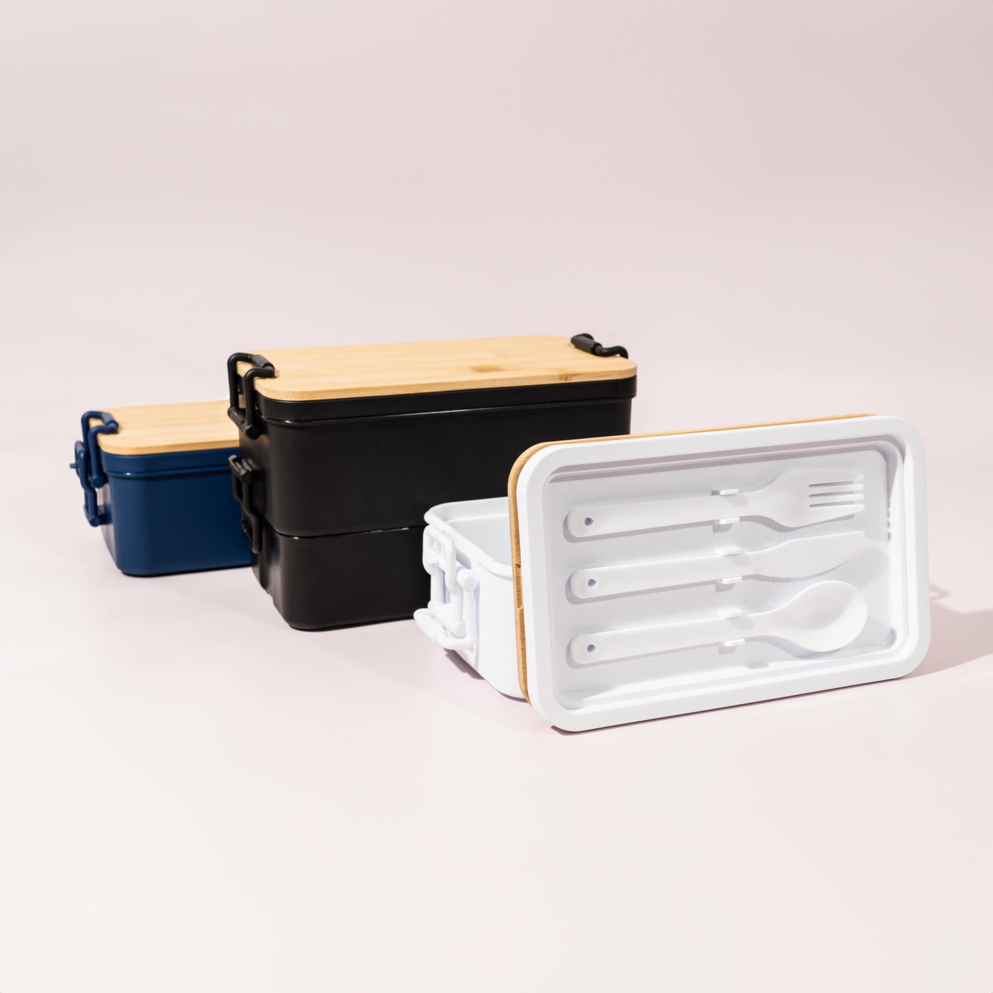 A double stack lunch box in blue, black, and white, featuring a bamboo lid and included utensils inside.