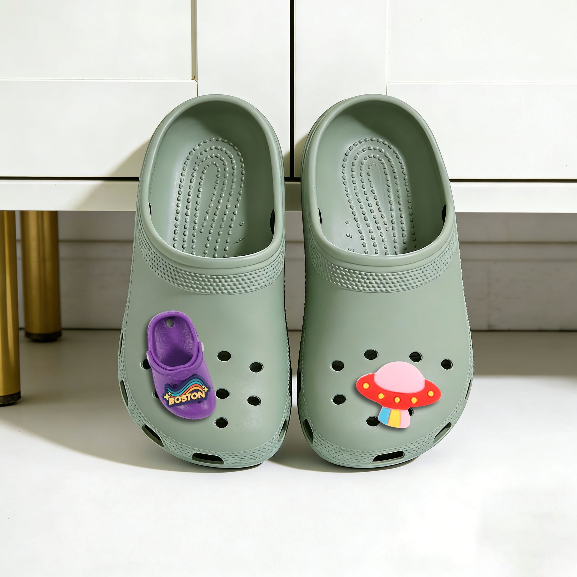 A pair of green clog shoes with colourful charms featuring a mushroom and a purple shoe design, set on a white surface.