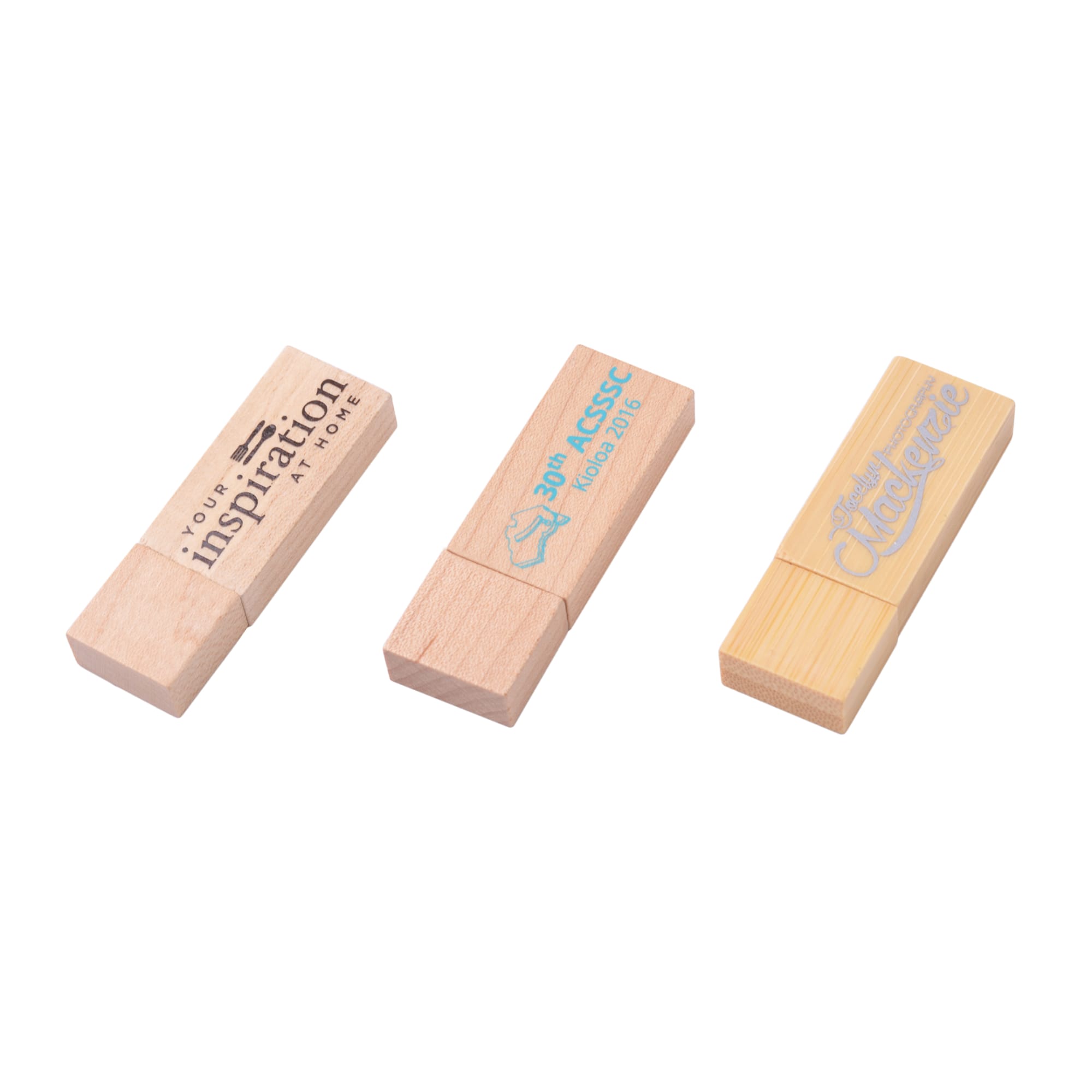 Three rectangular wooden flash drives in light wood tones, featuring varying designs and a branding logo on one.