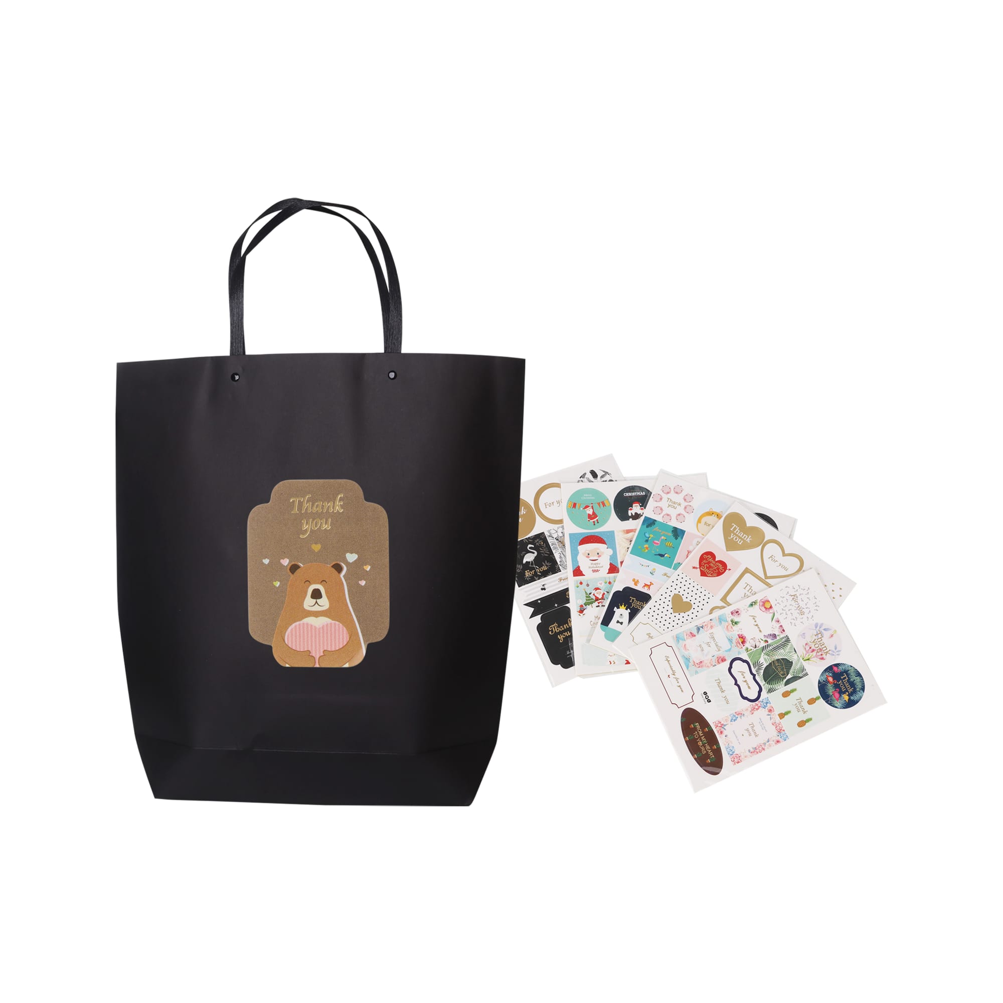 A large black boutique paper bag with handles and assorted decorative stickers displayed beside it.