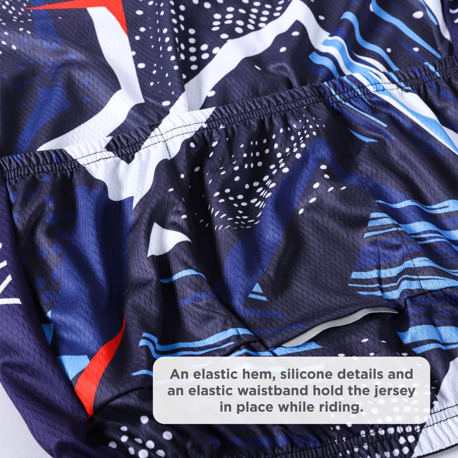 A close-up of a cycling jersey featuring a vibrant blue and abstract pattern, with an elastic hem and waistband.