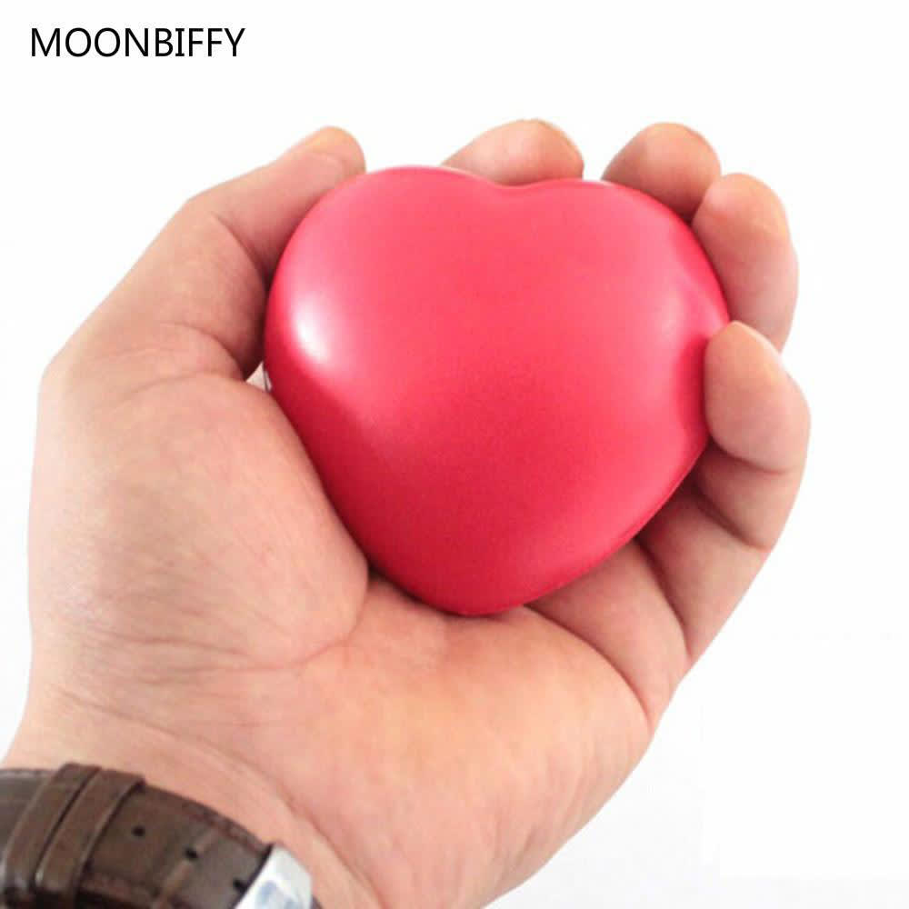 A red heart-shaped stress reliever held in a hand, featuring a smooth surface and a simple design.