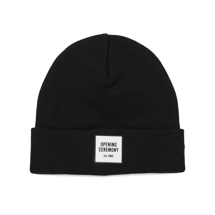 A black knitted beanie with a fold-up brim and a logo label on the front.