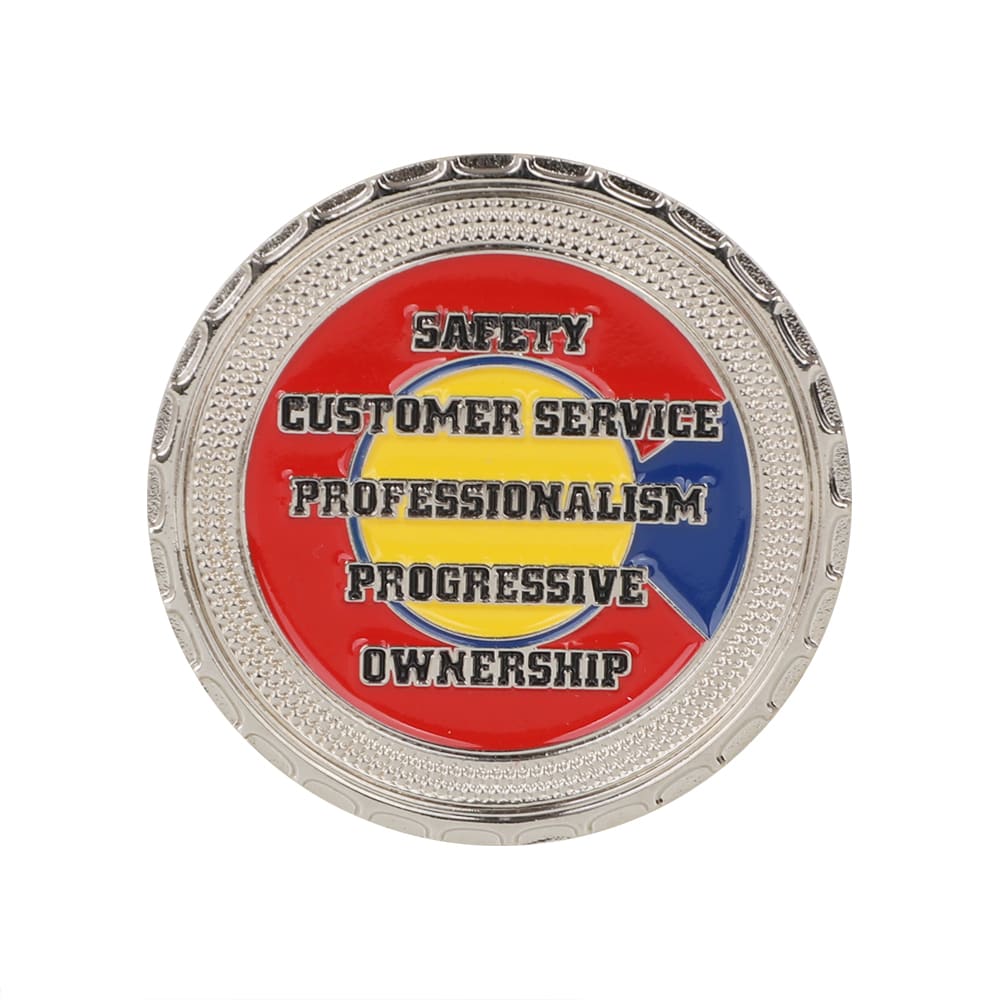 A commemorative gold coin pin with a red, blue, and yellow design featuring various phrases and a decorative border.