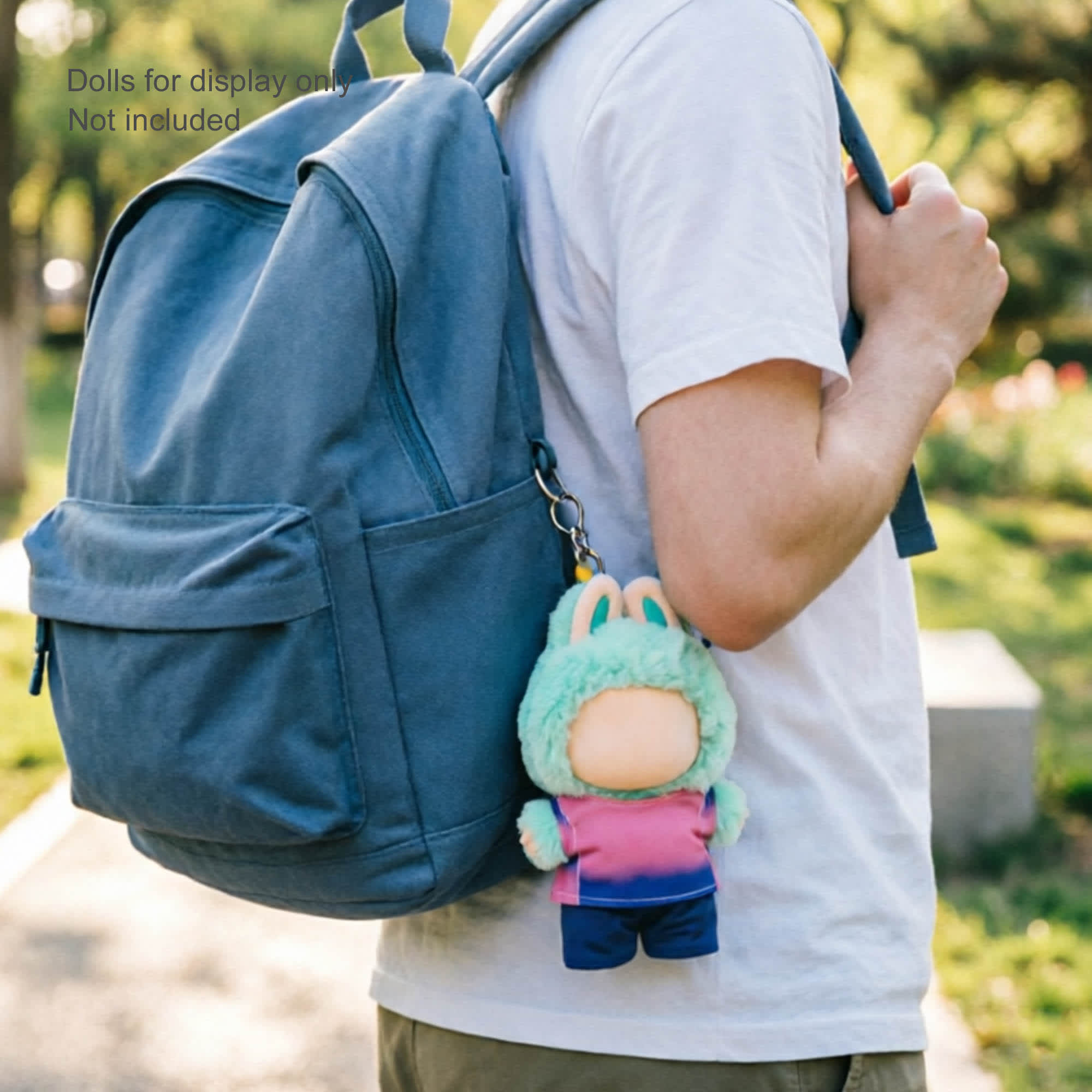 A plush doll in a green and pink outfit attached to a blue backpack, featuring a keychain.