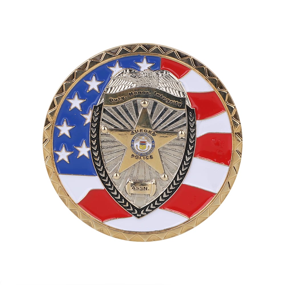 A commemorative gold coin pin featuring a shield design, accented with red, white, and blue elements, and a logo.