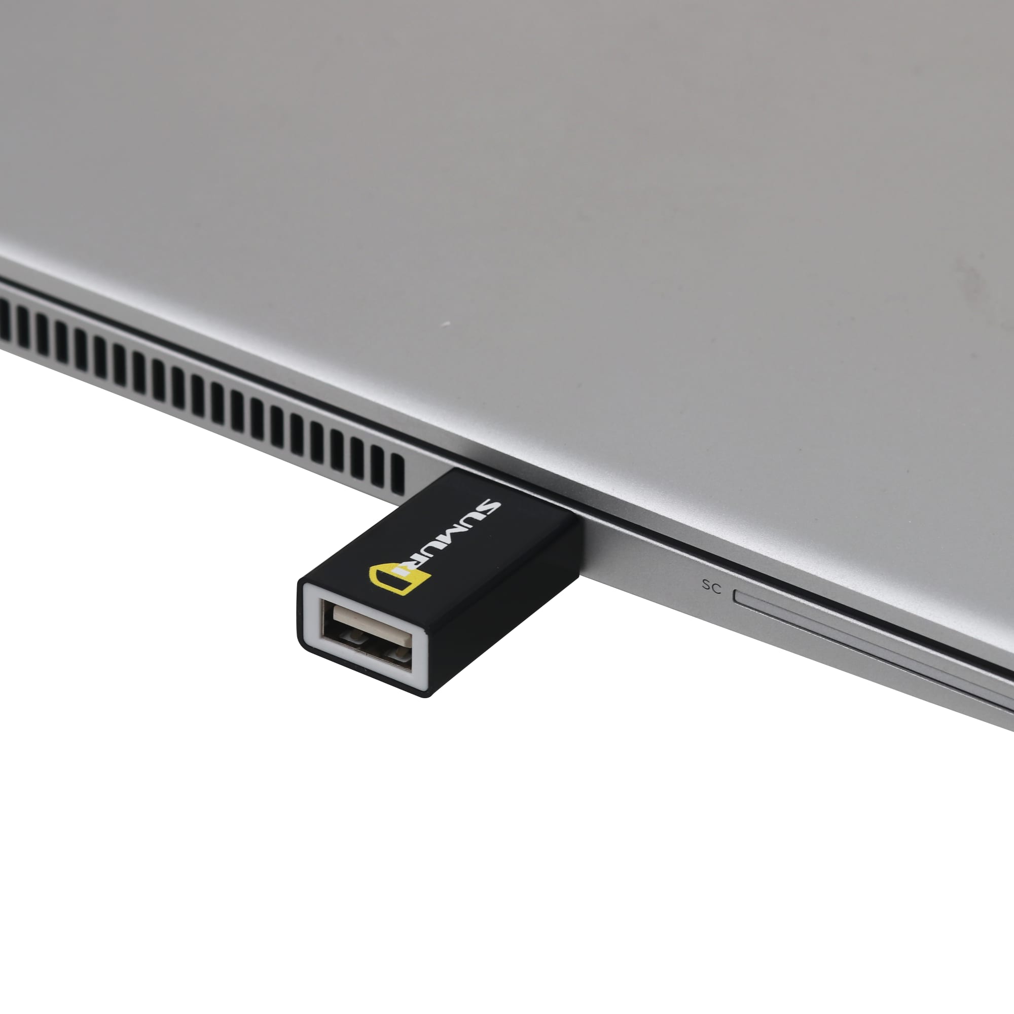 A black USB data blocker is plugged into a silver laptop, highlighting its sleek and compact design.