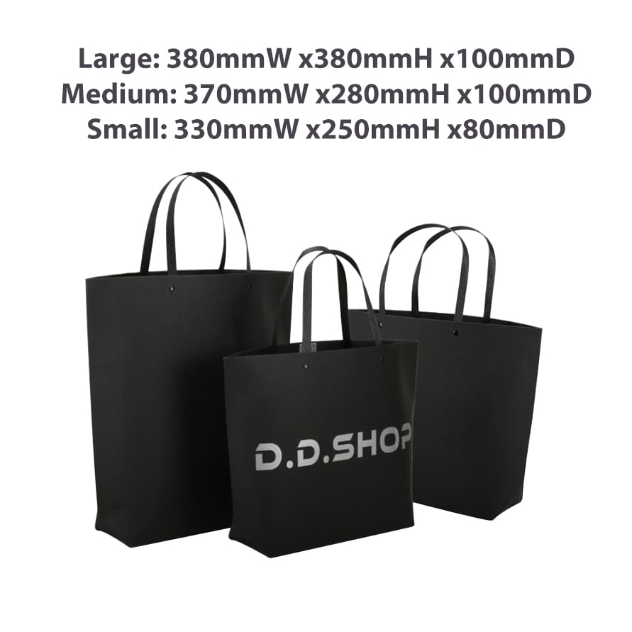 A medium black and white boutique paper bag with two black handles, displayed alongside larger and smaller bags.