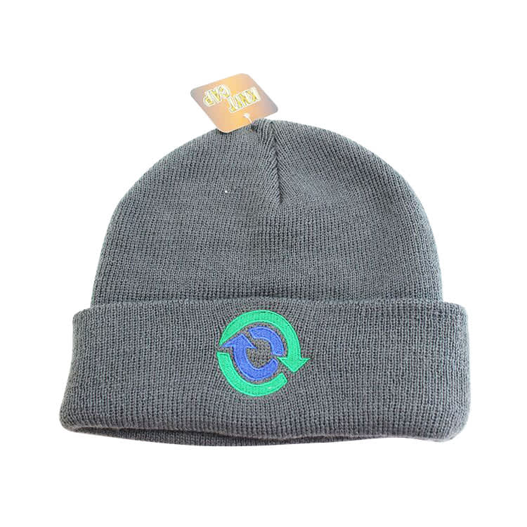 A grey knitted beanie with a folded cuff and a logo on the front.