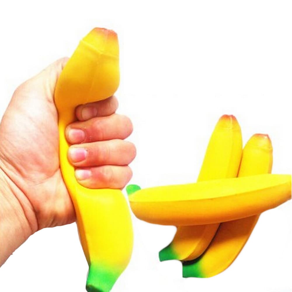 A hand squeezing a yellow banana-shaped stress reliever, alongside two additional bananas. The product has a smooth texture.