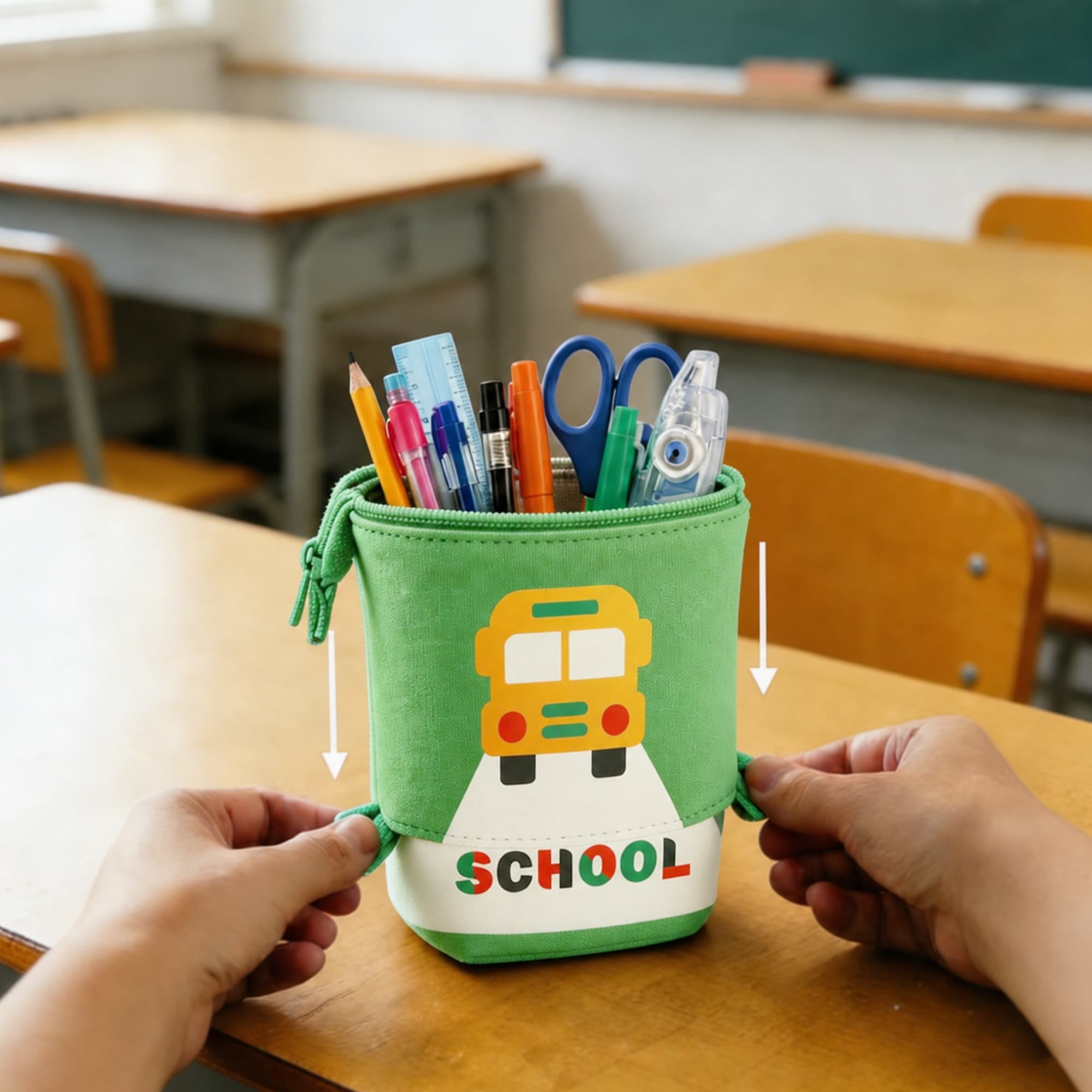 A green expandable pencil case featuring a school bus design, filled with pens, pencils, and scissors.
