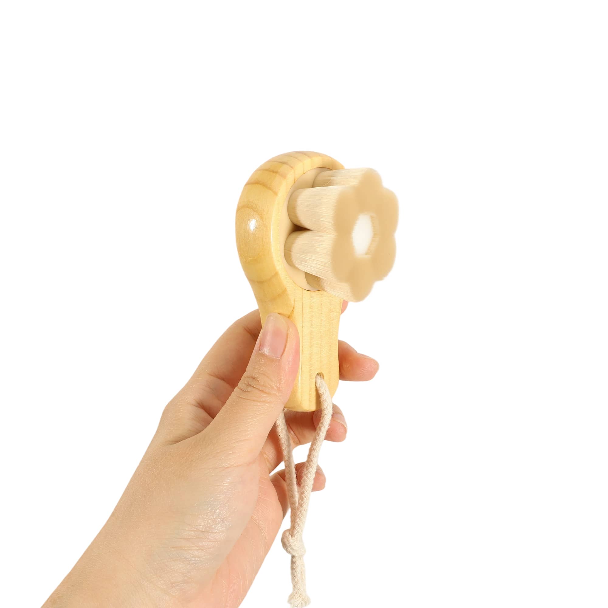 A wooden facial cleansing brush shaped like a flower, featuring a light wood finish and a string handle.