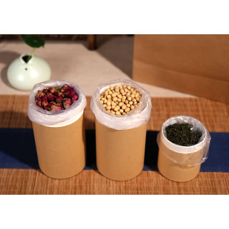 Three small paper cylinder boxes in brown, featuring plastic liners, filled with dried flowers, soybeans, and herbs.