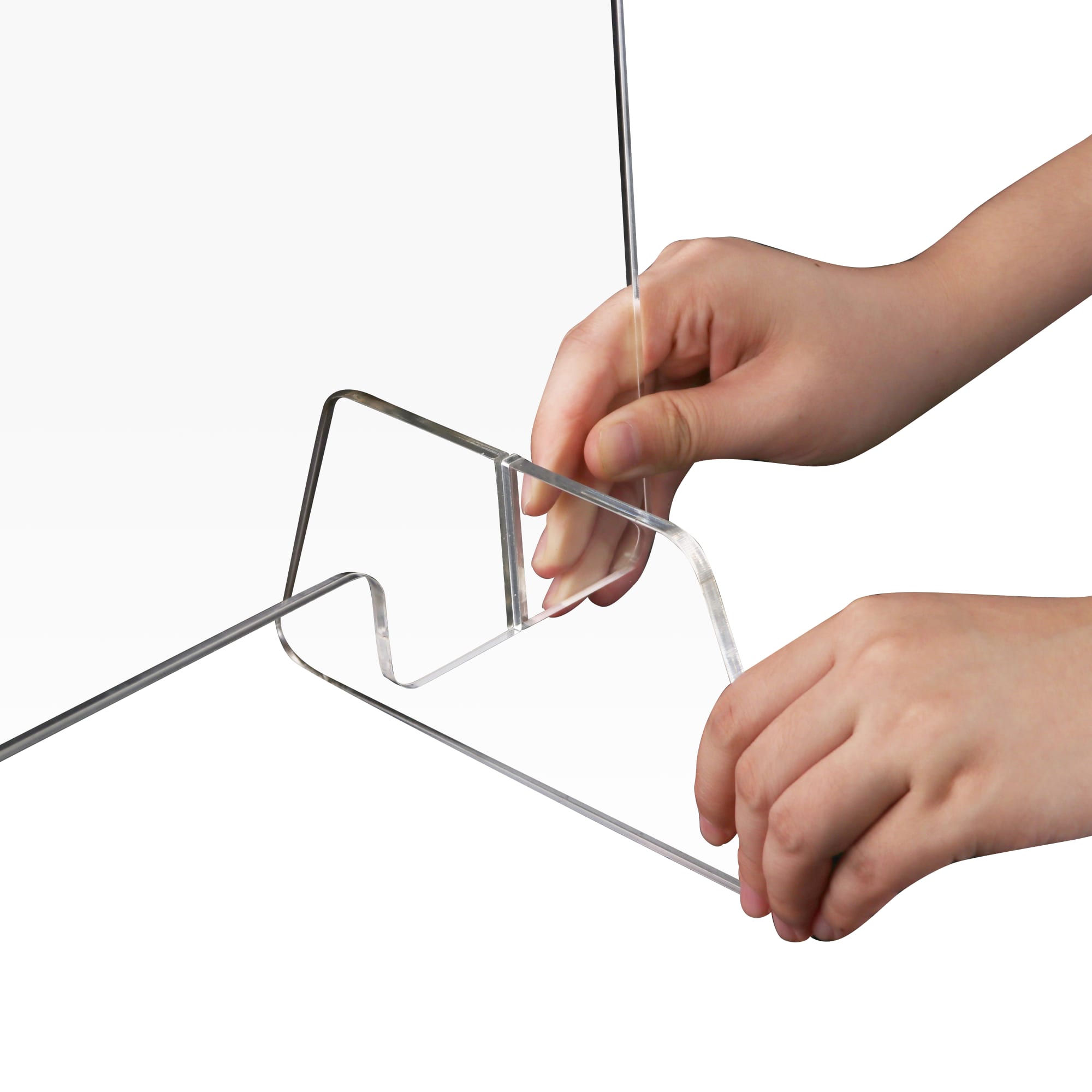 A clear acrylic personal protection screen is being assembled, held by hands at the base.