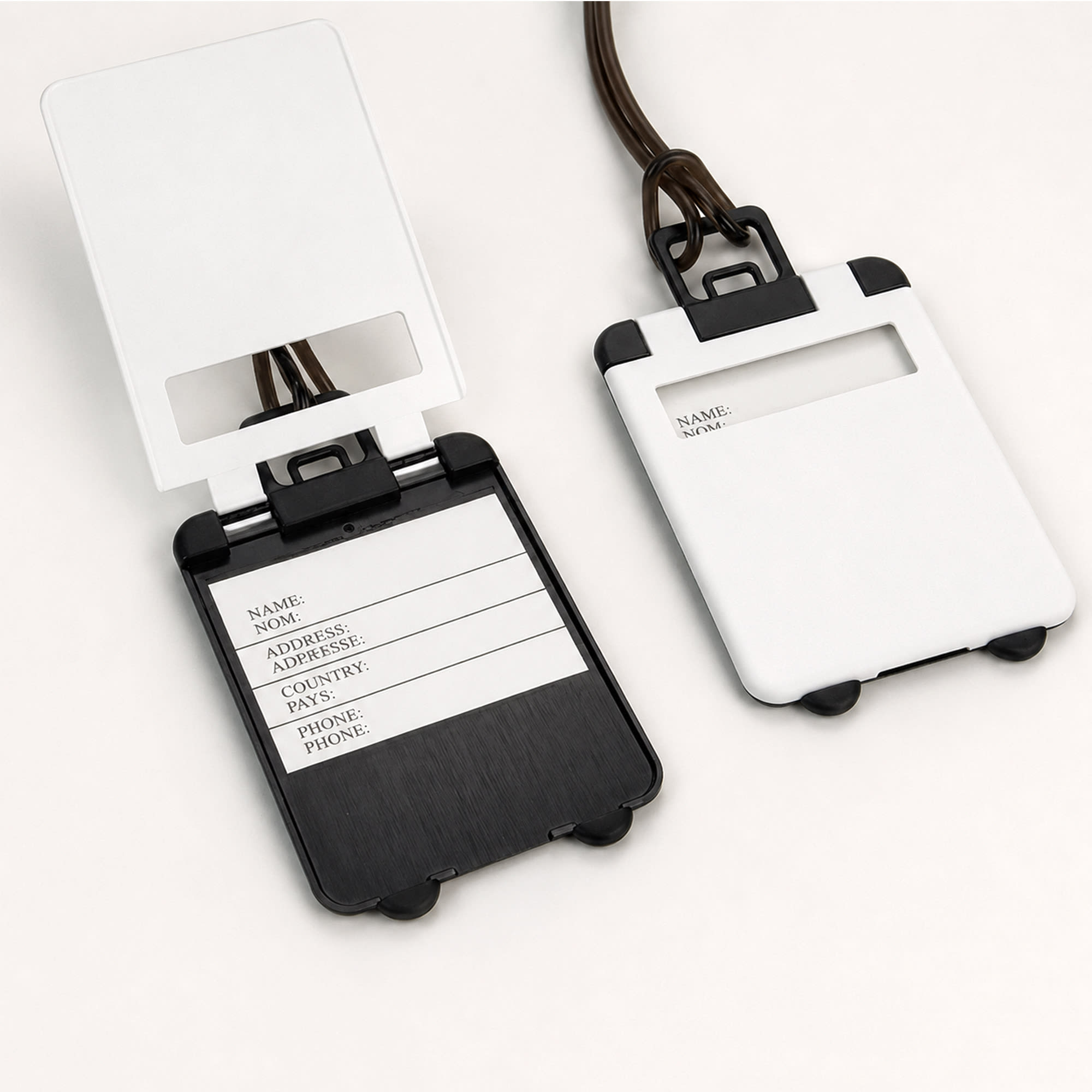A set of ABS luggage tags in white and black, featuring a clear window and space for personal details.