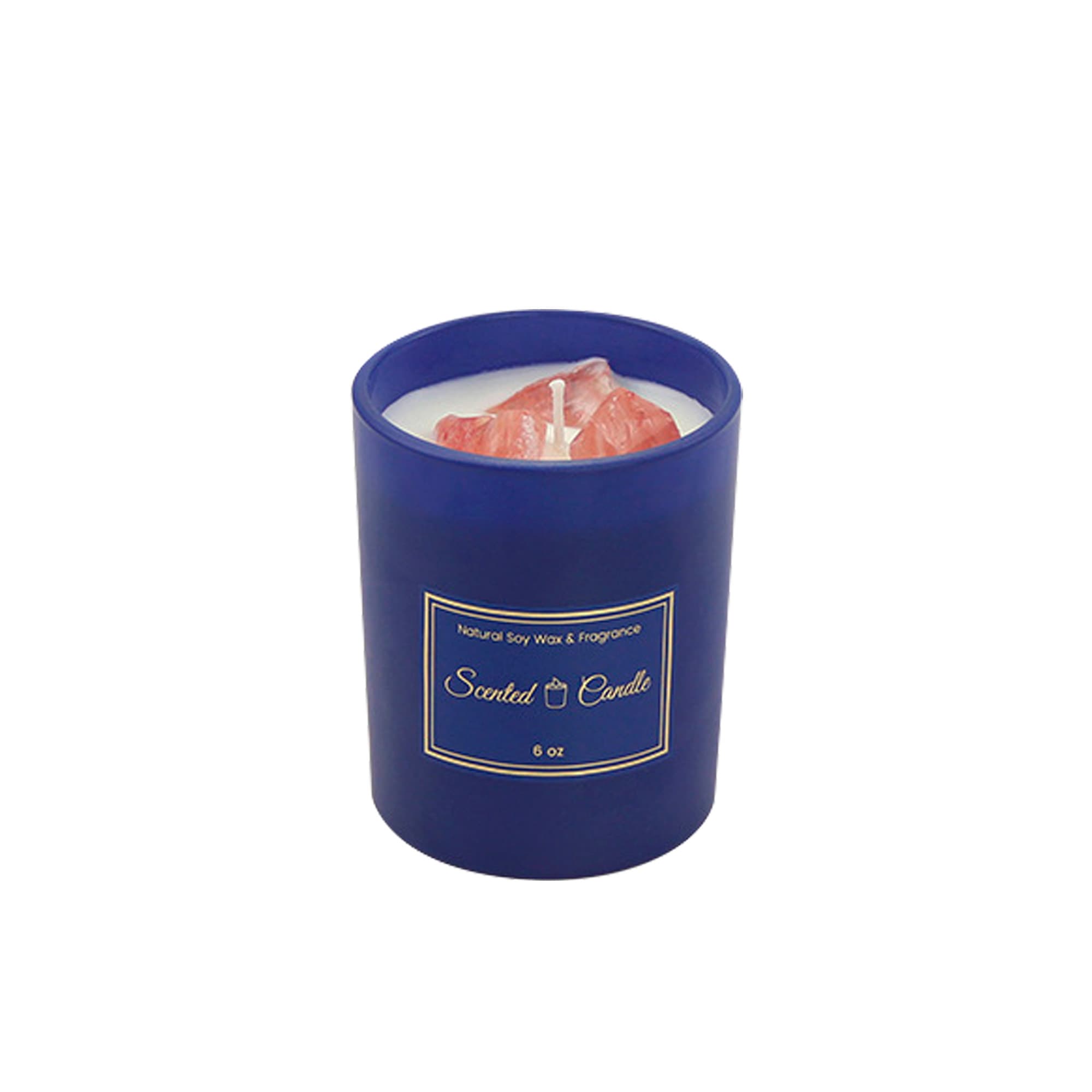 A blue glass candle with a natural soy wax interior and a wick, featuring a decorative design.