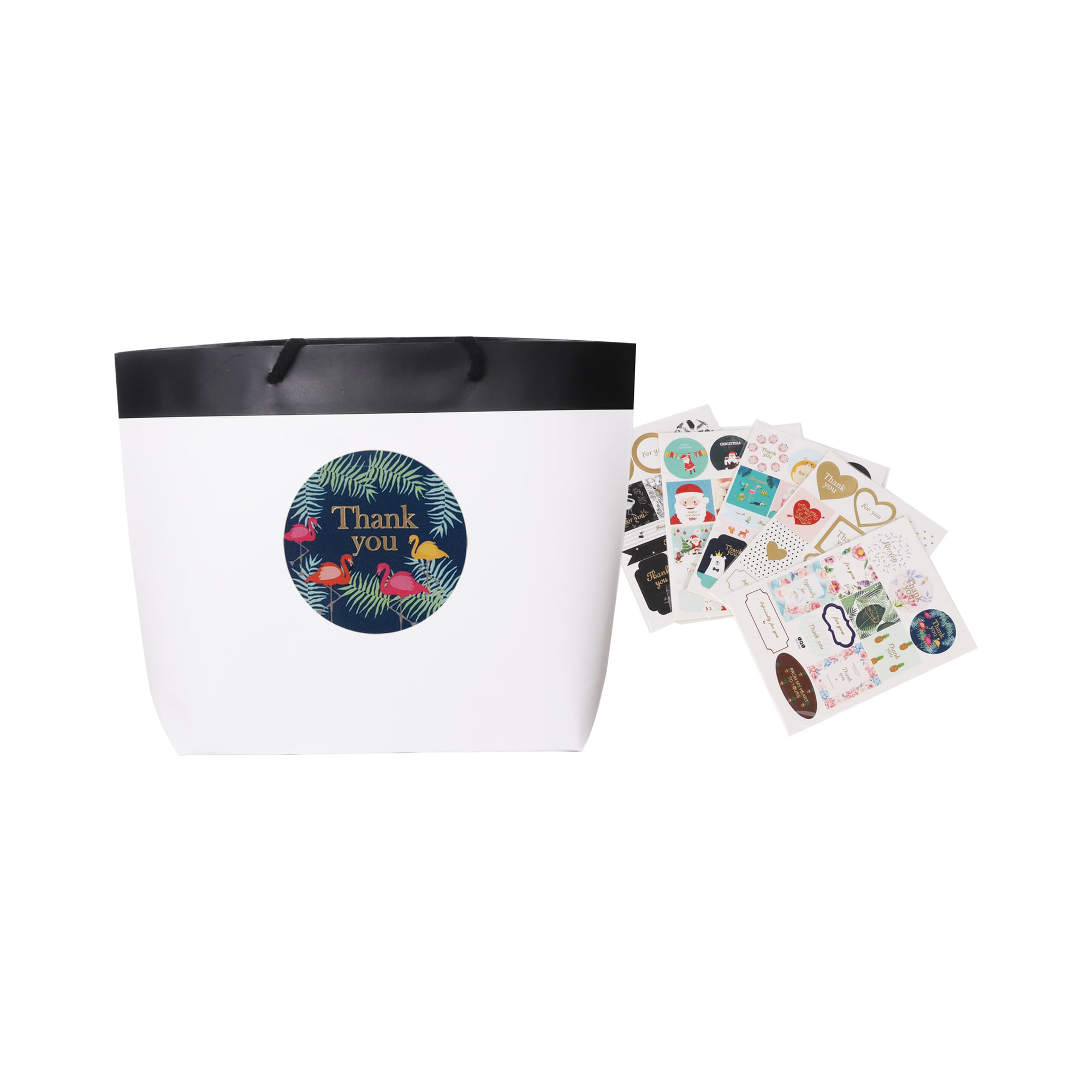 A small black and white boutique paper bag with a black rim and assorted decorative stickers beside it.