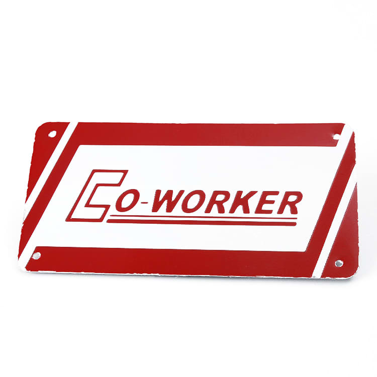 A rectangular licence plate in white and red featuring the word "CO-WORKER." It includes holes for mounting.