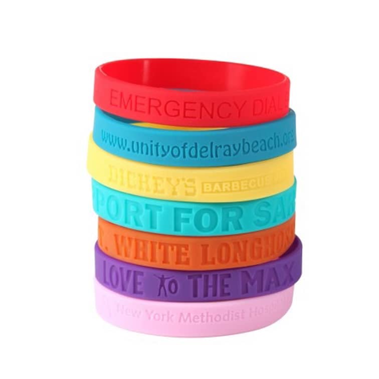 A stack of multicoloured debossed silicone wristbands in red, yellow, green, blue, orange, purple, and pink.
