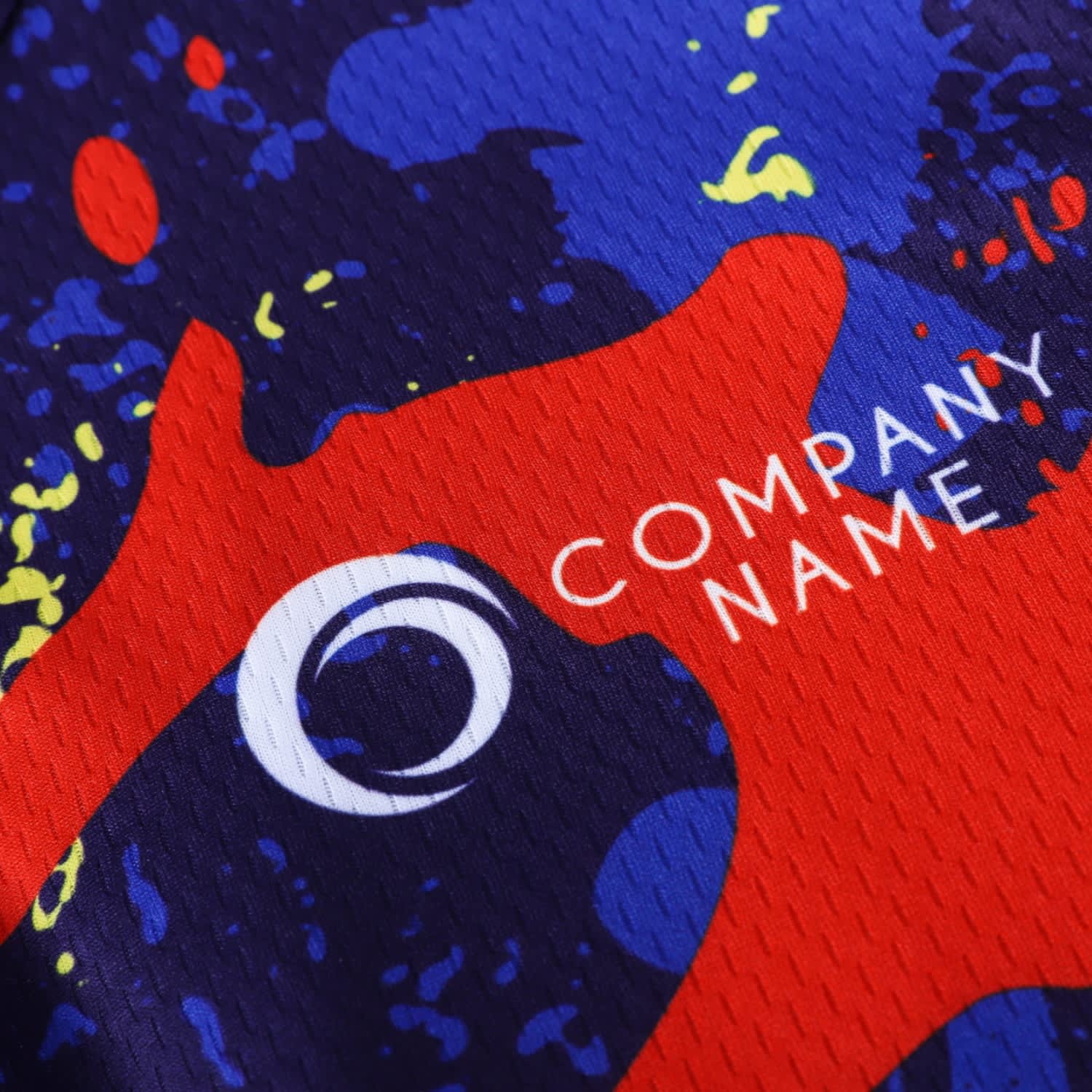 A close-up of a men's cycling jersey featuring a vibrant design with red, blue, and yellow splashes, and a logo.