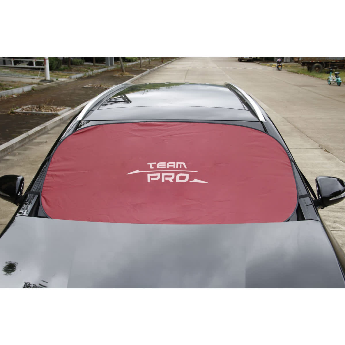 A red car shade covers the windshield of a parked vehicle, featuring a logo in the centre.