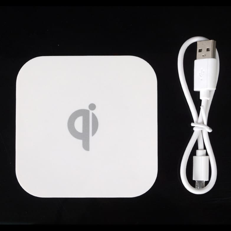 A square-shaped white wireless charger with a USB cable, featuring a simple logo on its surface.