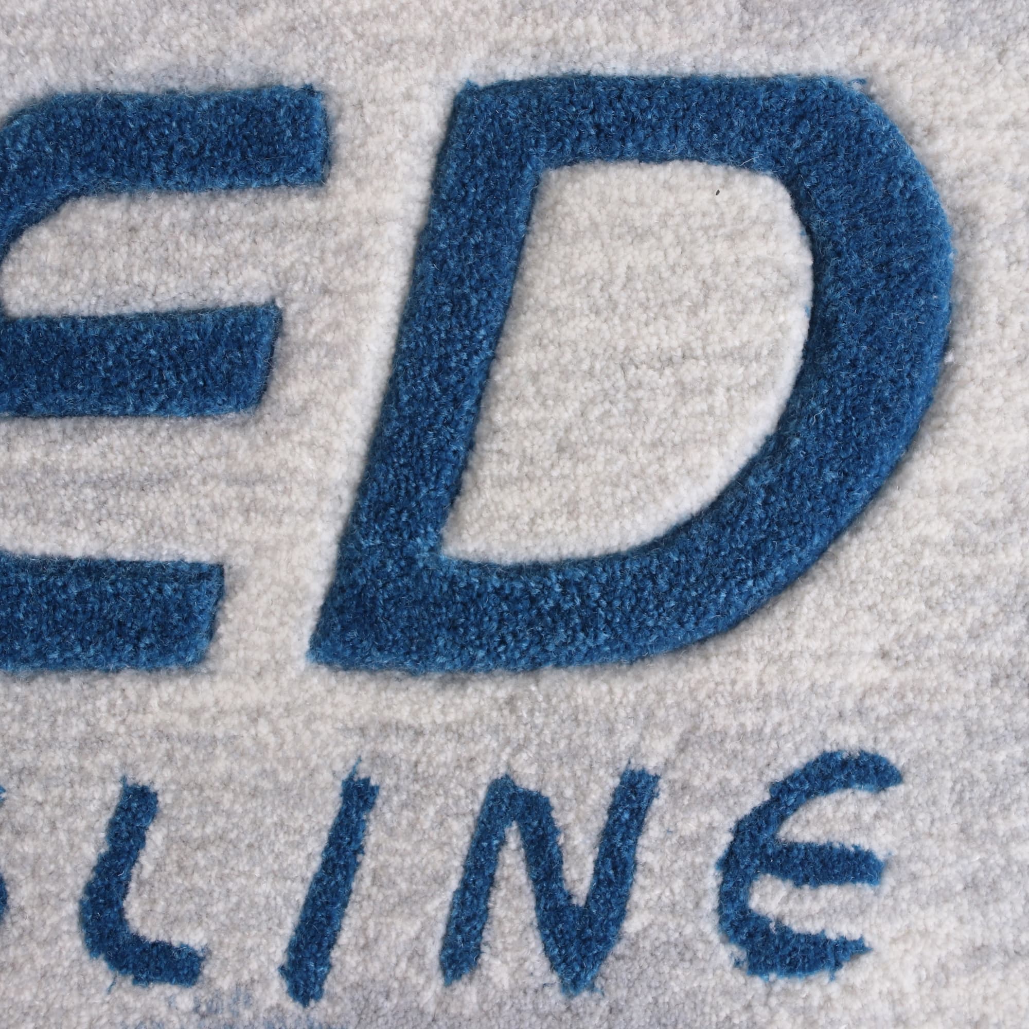Acrylic fibre logo mat in grey and blue, featuring a prominent logo design.