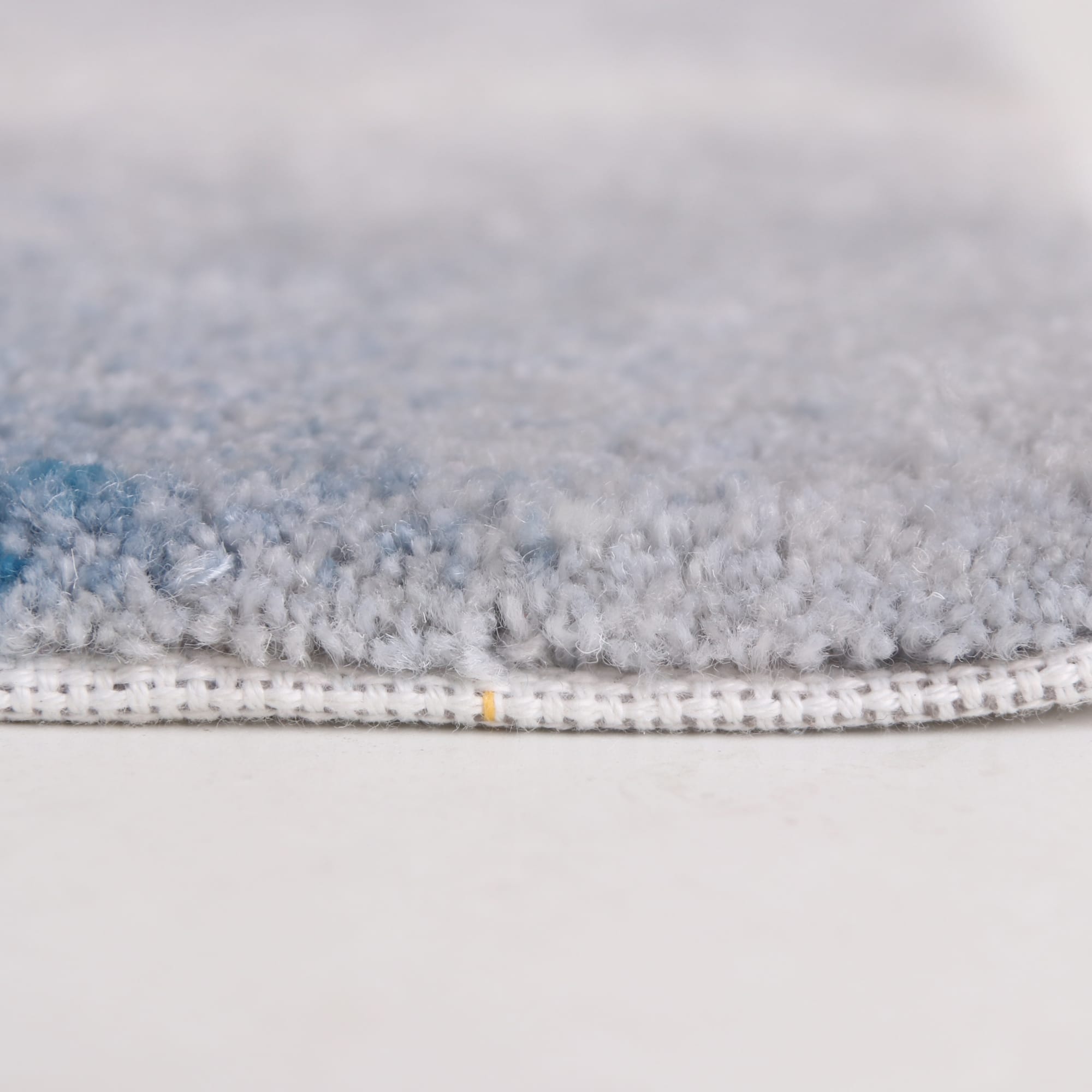 Acrylic fibre logo mat with a soft, textured surface in shades of grey and blue, featuring a stitched edge.